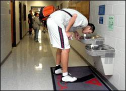 tall man struggles to use drinking fountain